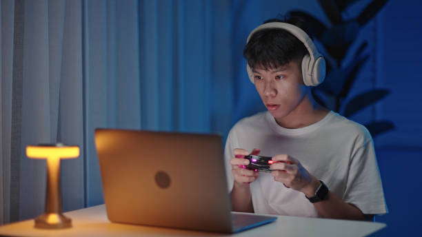 istock Teenager playing console games on laptop at night. 2157256257