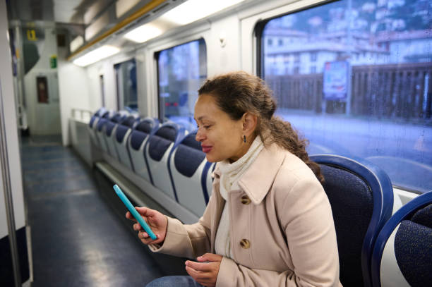 istock Woman smiling while looking at smartphone on train ride 2157256417
