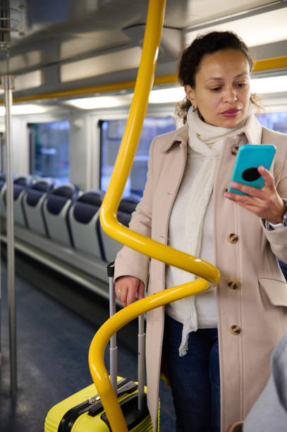 istock Woman with luggage checking phone while traveling on public transportation 2157256597