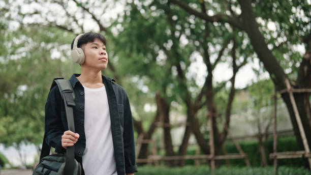 istock Teenager student walk at park while wearing headphones. 2157256857