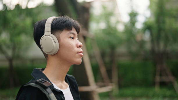 istock Teenager student walk at park while wearing headphones. 2157256861