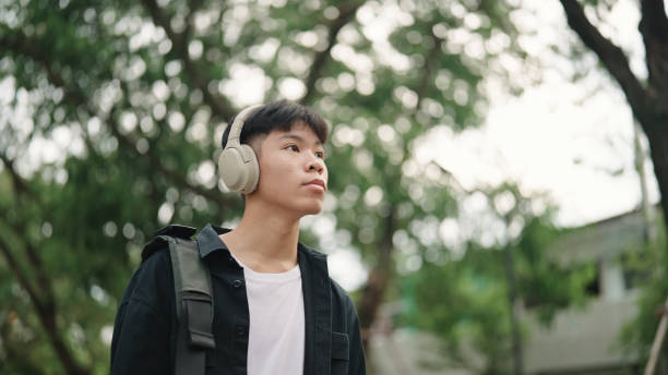istock Teenager student walk at park while wearing headphones. 2157256864