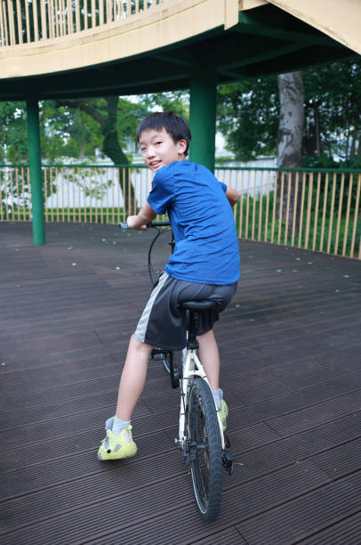 Rear view of two children having fun driving bicycle on the street during summer day