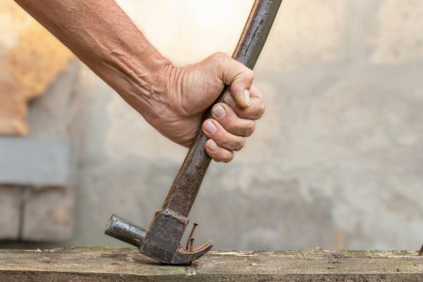 istock Pulling one bent nail out of a wooden board with a hammer, carpentry, workshop. 2157264466
