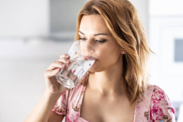 istock Young cute woman drinking pure water from glass in her kitchen. 2157264512