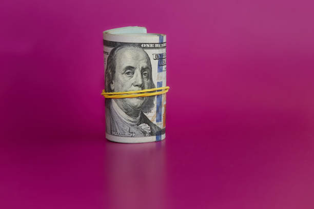 istock Rolled bundle of hundred-dollar bills on a pink background, hundred-dollar bills on a pink background, money for dreams, cash stash, illicit income 2157265716