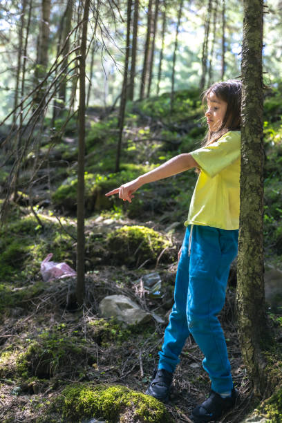 istock A girl points her finger at a plastic bag in the forest. 2157269137