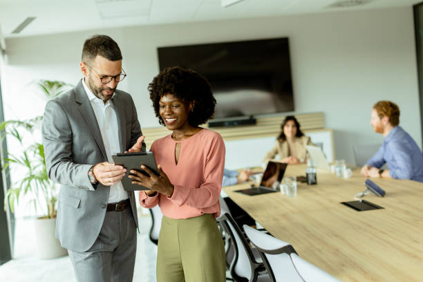 istock Joyful colleagues sharing a laugh over a tablet in a modern office meeting room 2157271012