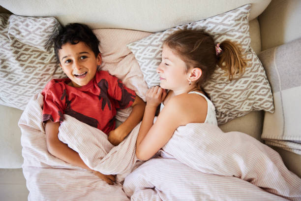 istock Smiling little boy lying with his older sister on a sofa at home 2157274609