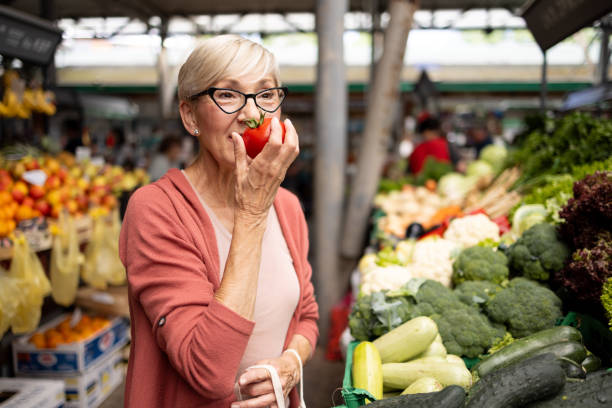 Woman sniffing a tomato at a market