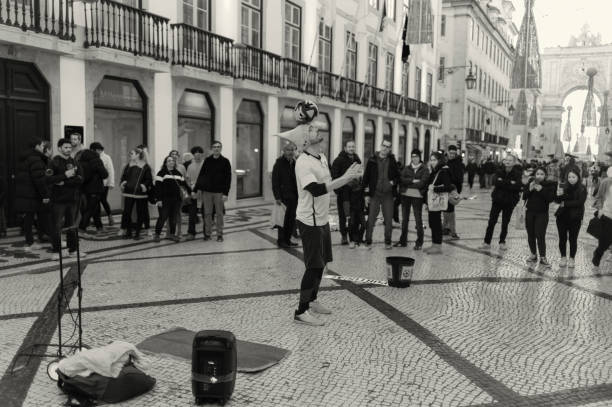 Lisbon, Portugal - December 23, 2023: A street artist performs a juggling act with a soccer ball at the Rua Augusta street in Lisbon downtown.