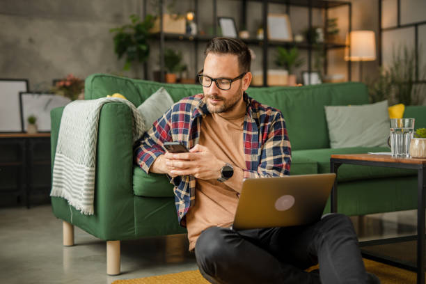 istock One men sitting on the floor, holding papers and working from home on a laptop, using technology concept 2157278440