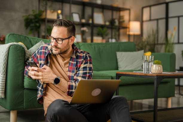 istock One men sitting on the floor, holding papers and working from home on a laptop, using technology concept 2157278442