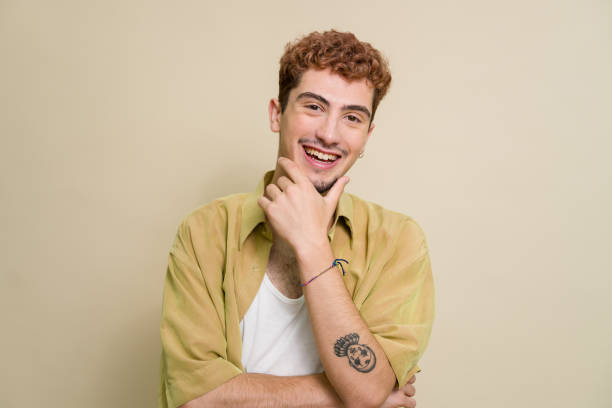 istock Young man with tattoos smiling and touching chin 2157278464