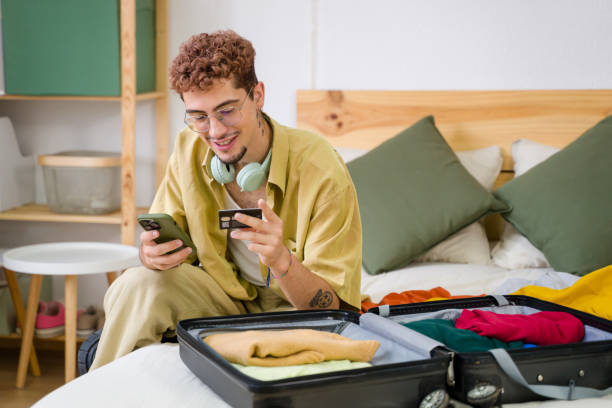 istock Young man using smartphone and credit card booking hotel room online 2157278722