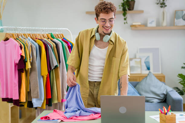 Fashion designer preparing online sales using laptop in his workshop