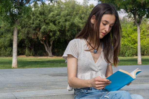 istock Relaxed Young College Girl Reading on Campus Grass 2157284579