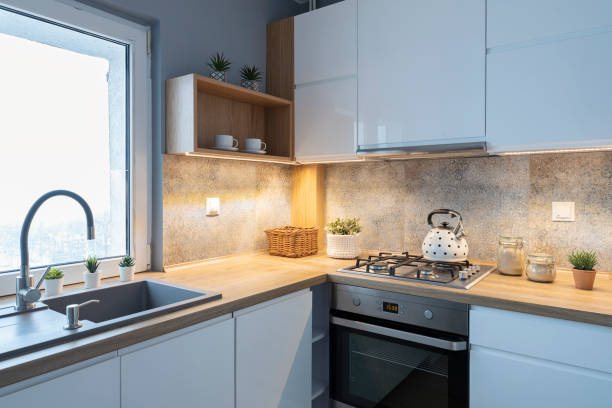 istock Modern kitchen in bright interior with wooden countertop, glass-ceramic stove top with kettle and pattern tile on the wall. Home decor. 2157288044