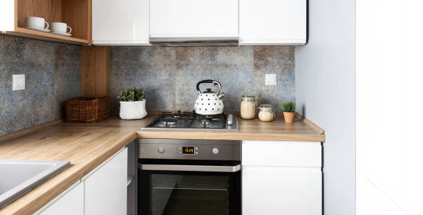 istock Modern kitchen in bright interior with wooden countertop, oven with kettle and pattern tile on the wall. Home decor. 2157288049