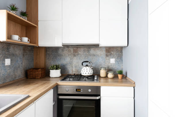 istock Modern kitchen in bright interior with wooden countertop, oven with kettle and pattern tile on the wall. Home decor. 2157288066
