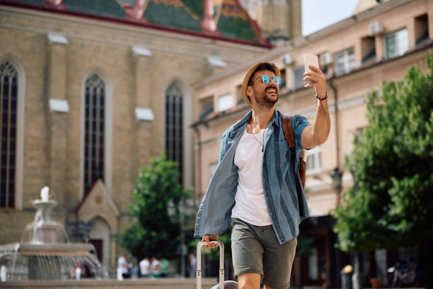 istock Happy tourist using cell phone while taking selfie on town square. 2157291761