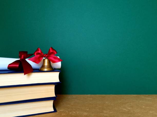 istock Bell and diploma decorated with ribbons on a stack of books 2157292933