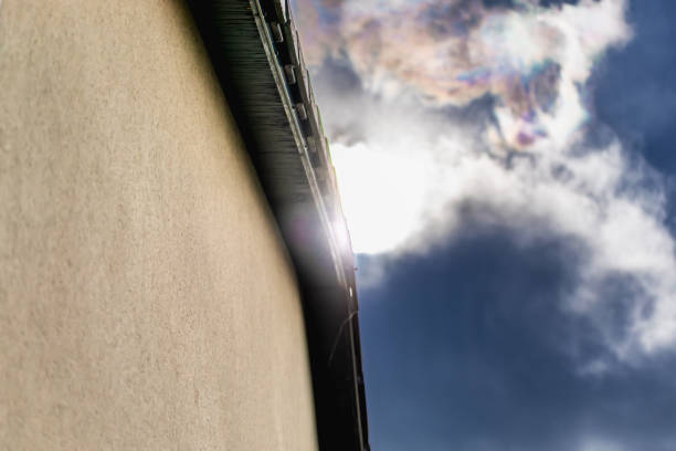 Sun and blue sky behind a roof edge seen from below