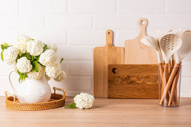 istock Modern kitchen background in light colors. A set cutting board on a wooden countertop. A spring flowering branches in a jug. Front view. 2157296650