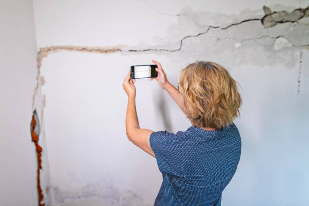 istock Woman looking at a wall damaged after the earthquake 2157301627
