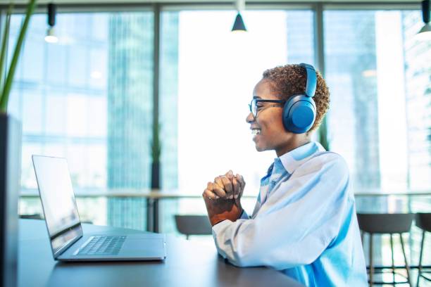 Video call with HR manager: job interview Young adult Black woman having job interview online using laptop in modern coworking new hire stock pictures, royalty-free photos & images