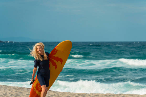 Female surfer carrying her board on the beach