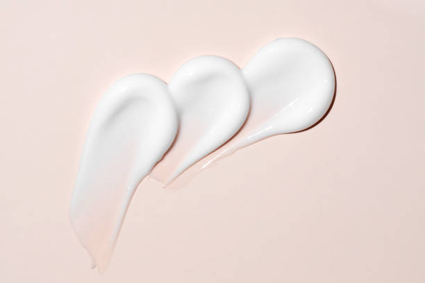 istock cream stroke isolated on beige background. White drops cream smear smudge sample. face or body skincare product swatch. showcase of the product 2157308263