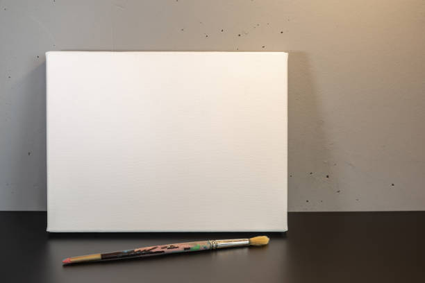 istock Blank white canvas with a brush on a black surface on a gray background. 2157309406