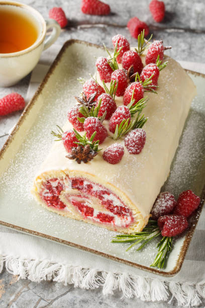 istock Christmas Raspberry Cake Roll a light and fluffy vanilla sponge cake rolled up with a cream cheese filling, raspberry jam and fresh berry closeup on the plate. Vertical 2157318727