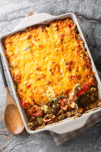 istock John Wayne Casserole is a taco beef cooked in biscuit dough with sour cream, Cheddar cheese, tomatoes, and bell peppers closeup on the baking dish. Vertical top view 2157318816