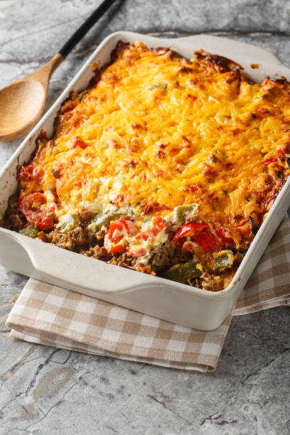 istock John Wayne Casserole is a delicious taco beef casserole cooked in biscuit dough with sour cream, Cheddar cheese, tomatoes, and bell peppers closeup on the baking dish. Vertical 2157318883