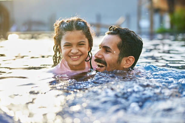 istock Cheerful girl swimming with father in pool 2157321041