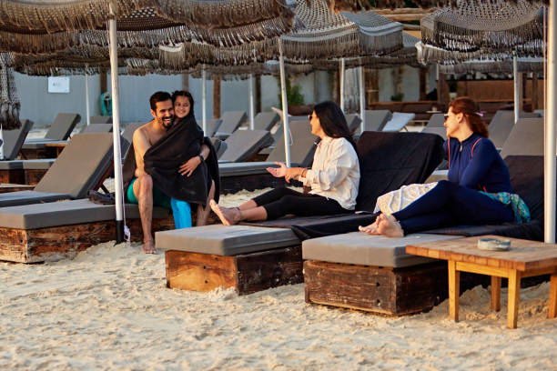 Happy family sitting on lounge chairs and enjoying vacations at beach