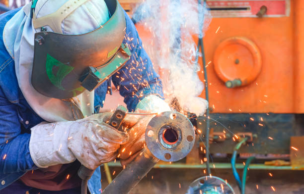 istock Welder welding metal flange to connect with steel pipe for using as improvement material in oil pipeline systems maintenance work 2157321466