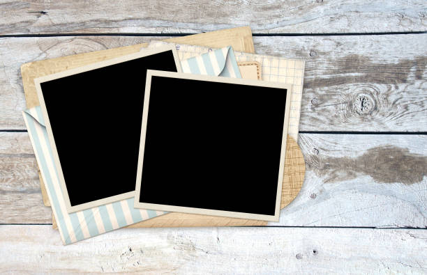 istock Two retro photo frame, vintage card and envelope on old wooden board. Nostalgic scrapbooking style. Mock up template. Copy space for text 2157322871