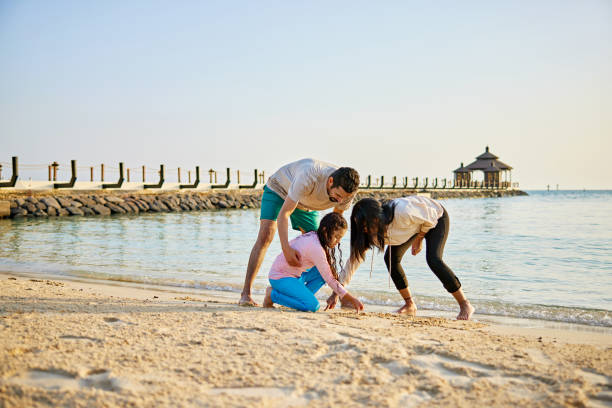 istock Parents with daughter playing in sand at beach 2157323108