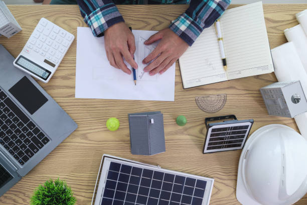istock Engineers are reviewing plans from architects to prepare to install solar panels and wind turbines on the building to efficiently produce electricity using the concept of green energy from solar cells 2157323381