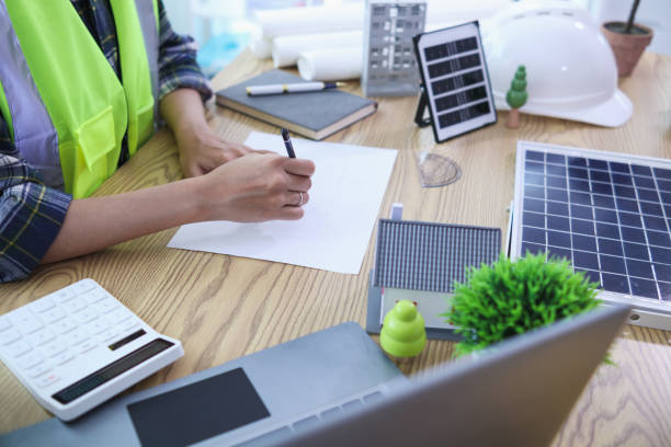 istock Engineers are reviewing plans from architects to prepare to install solar panels and wind turbines on the building to efficiently produce electricity using the concept of green energy from solar cells 2157323590