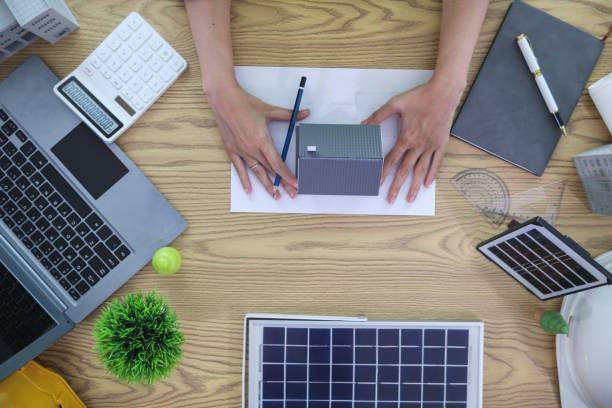 istock Engineers are reviewing plans from architects to prepare to install solar panels and wind turbines on the building to efficiently produce electricity using the concept of green energy from solar cells 2157324255