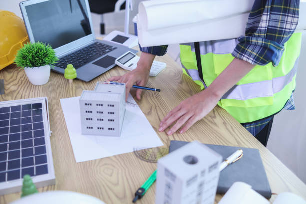 istock Engineers are reviewing plans from architects to prepare to install solar panels and wind turbines on the building to efficiently produce electricity using the concept of green energy from solar cells 2157324289
