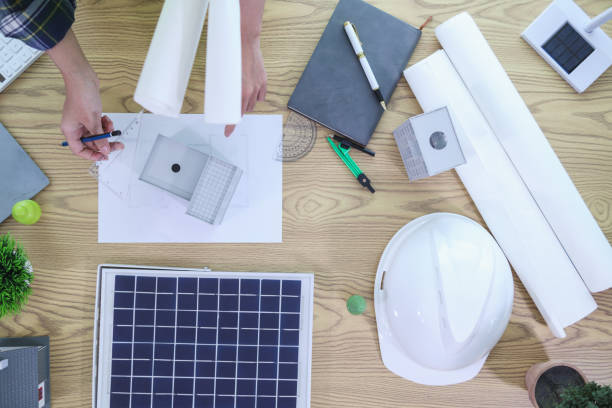 istock Engineers are reviewing plans from architects to prepare to install solar panels and wind turbines on the building to efficiently produce electricity using the concept of green energy from solar cells 2157324300