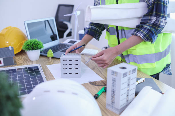 istock Engineers are reviewing plans from architects to prepare to install solar panels and wind turbines on the building to efficiently produce electricity using the concept of green energy from solar cells 2157324305