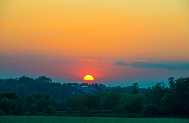 Tranquil golden sunset illuminating a picturesque view of rolling hills and fields in the english countryside