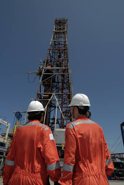 Drilling oil rig derrick working at sea, two workers in first plane, Campos Basin, Brazil.