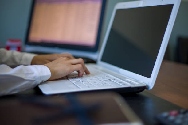 Short-haired businesswoman in white shirt working at the computer at her desk in the office, making phone calls and reviewing files with the tablet